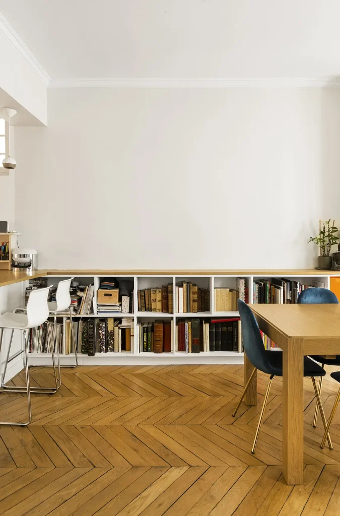 Salon d'un appartement rénové, rangement, grande table et chaise bleue